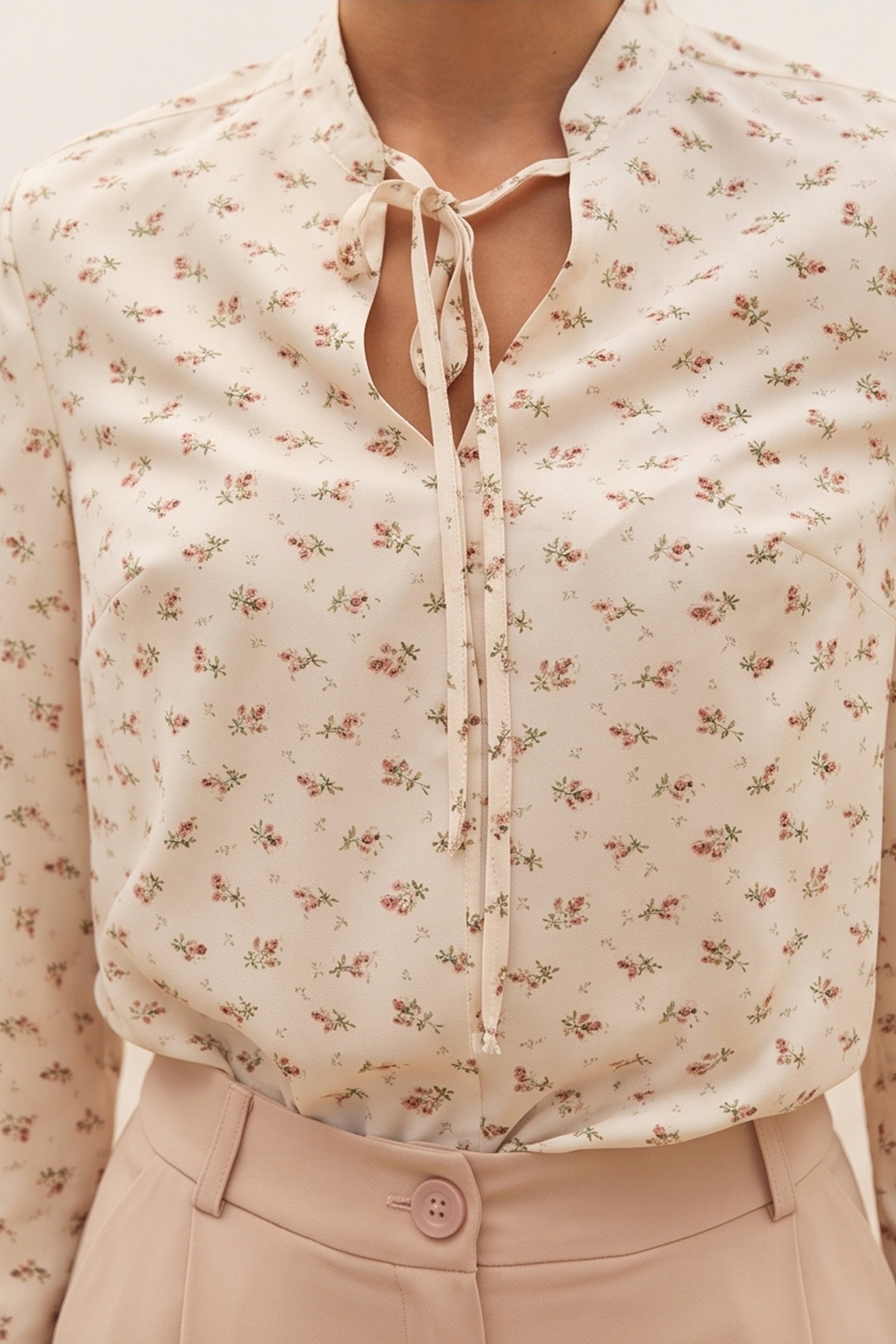 Close up view of a woman wearing the white Floral Blouse by FemeAdor featuring a delicate floral print and tie detail, perfect for casual or polished looks