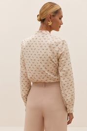 Back view of a woman wearing the white Floral Blouse by FemeAdor featuring a delicate floral print and tie detail, perfect for casual or polished looks