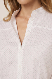 Close up view of a woman wearing the white Liora Midi Dress by FemeAdor with polka dots, featuring a button-down front and flattering belted waistline