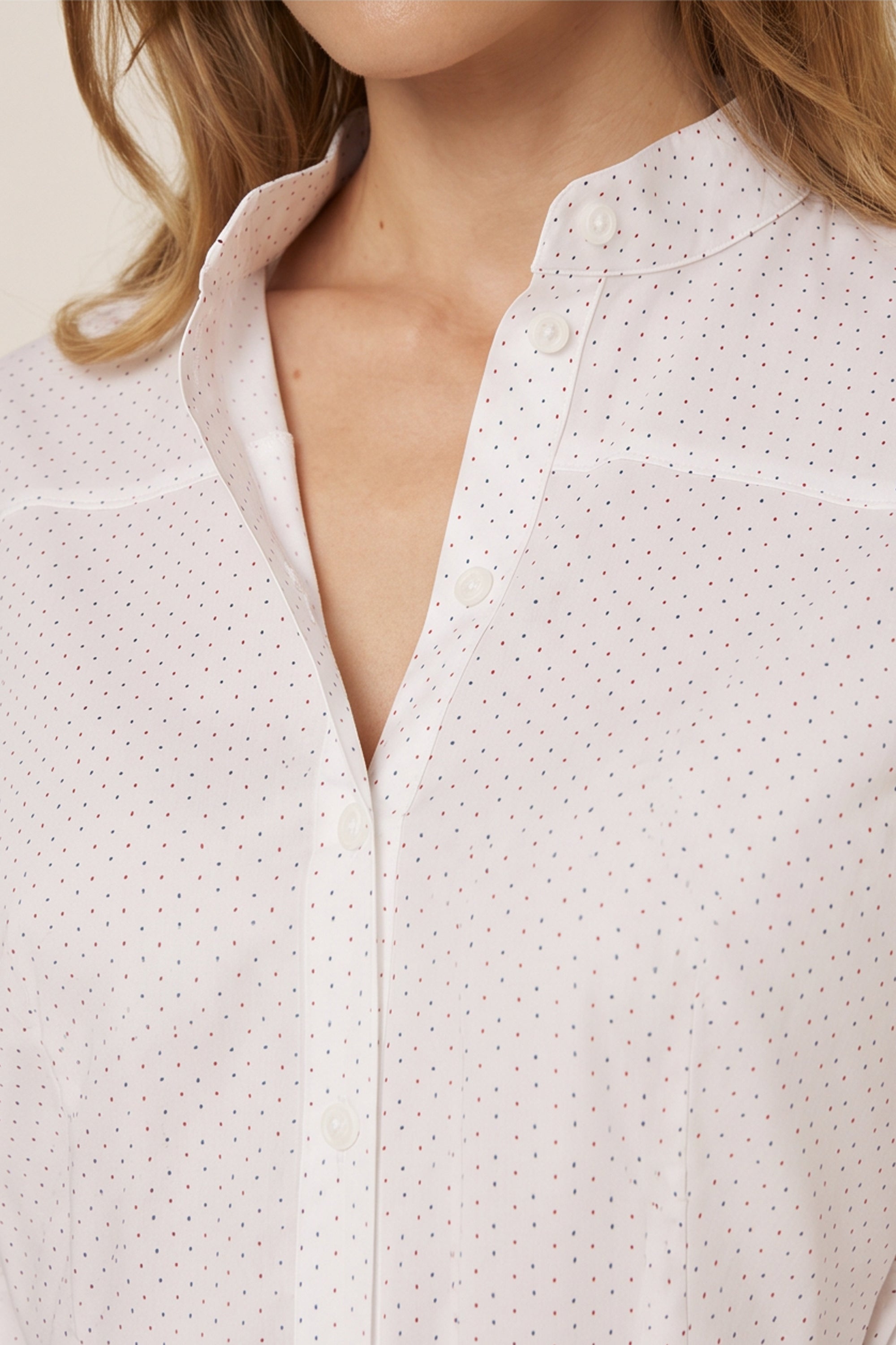 Close up view of a woman wearing the white Liora Midi Dress by FemeAdor with polka dots, featuring a button-down front and flattering belted waistline