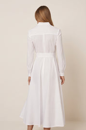 Back view of a woman wearing the white Liora Midi Dress by FemeAdor with polka dots, featuring a button-down front and flattering belted waistline