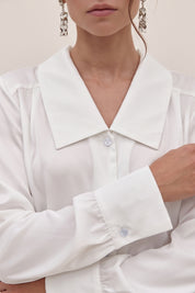 Close up view of a woman wearing the white Timeless Blouse by FemeAdor featuring a flattering fit, ideal for layering or wearing solo in professional and casual settings.