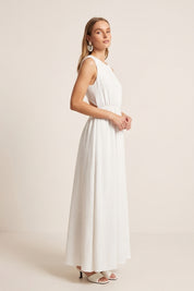 Side view of a woman wearing the white Virella Maxi Dress with sleeveless design, open back, and floor-length silhouette for elegant evening wear