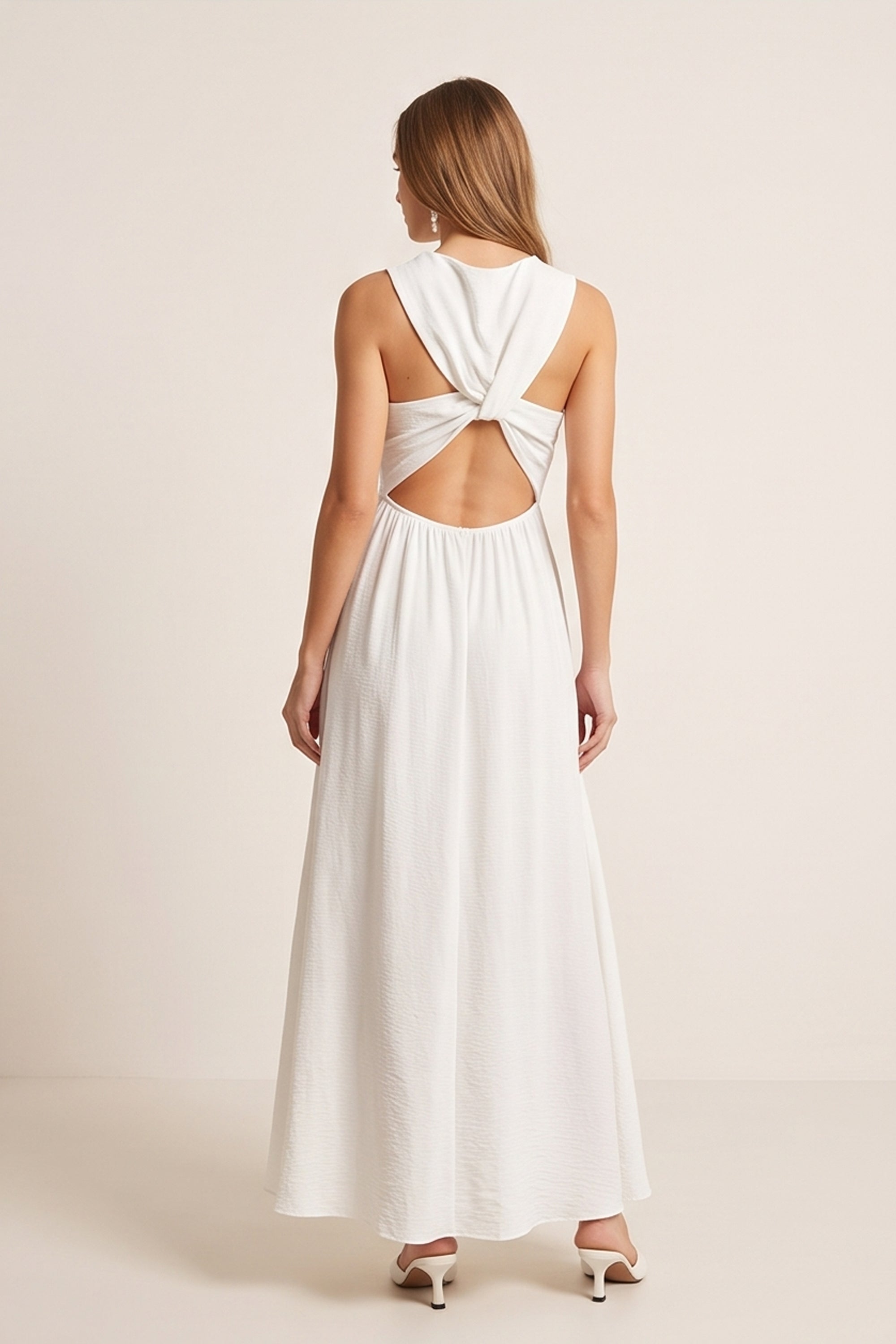 Back view of a woman wearing the white Virella Maxi Dress with sleeveless design, open back, and floor-length silhouette for elegant evening wear